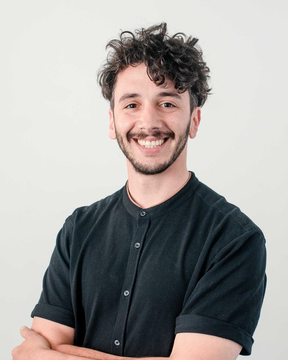 Martín Saavedra, de camisa negra, sonriendo con los brazos cruzados